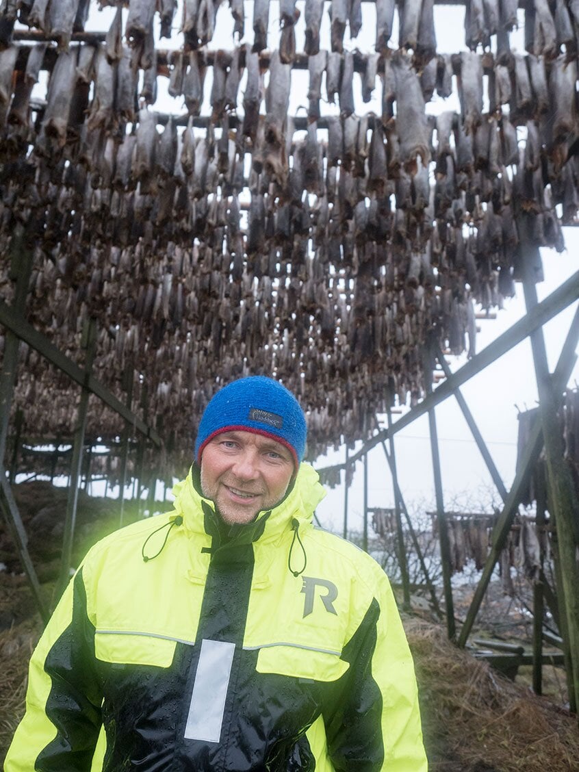 Pettersen under a drying rack for stockfish
